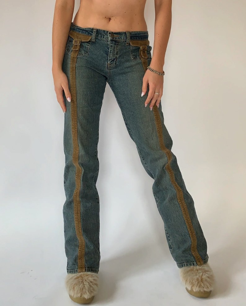 Front view of low-rise flare jeans with brown suede stripe trim panels running down both legs, worn with fluffy slippers